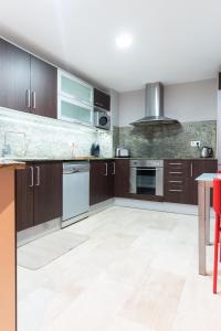 an empty kitchen with wooden cabinets and a table at Apartament Granollers Up Live I in Granollers