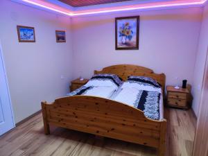 um quarto com uma cama de madeira e 2 mesas de cabeceira em Faluvégi Vendégház Szentgyörgyvár em Szentgyörgyvár