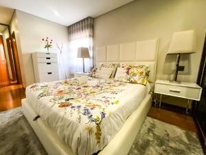 um quarto com uma grande cama branca e uma colcha floral em Mar&Sal Vila do Conde em Vila do Conde