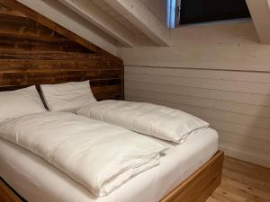 1 cama con sábanas blancas y almohadas en una habitación en Camelot Luxury Houses Horses en Pellizzano