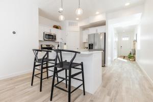 a kitchen with white cabinets and black bar stools at Brand New Garden City 3BR 2BA BOAT PARKING in Garden City