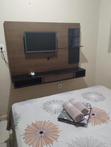 1 dormitorio con TV y 1 cama con toallas en Suites Jatiuca en Maceió