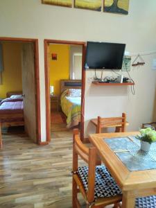 a living room with a table and a tv and a bedroom at Cabaña Tranquila in Villarrica