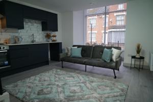 ein Wohnzimmer mit einem Sofa und einer Küche in der Unterkunft Station Road Stays - 1 & 2 bed apartments - Desborough, Kettering in Kettering
