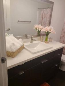 a bathroom with a sink and a mirror and pink flowers at 2bedroom Downtown Los Angeles pool and gym onsite. in Los Angeles