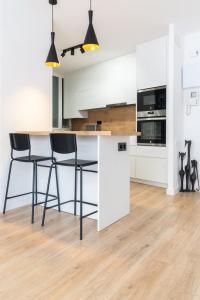 uma cozinha com armários brancos e bancos de bar pretos em Apartment Granollers Up Live II em Granollers