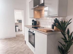 a white kitchen with a stove top oven next to at Coronation House by Solace Stays in Merthyr Tydfil