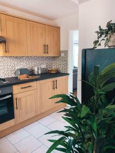 een keuken met houten kasten en een potplant bij Grosvenor House by Solace Stays in Newport