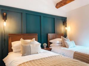 Falls Cottage by Solace Stays في ميرثير تيدفيل: سريرين في غرفة بجدران زرقاء