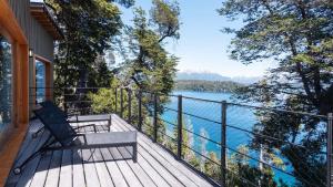a wooden balcony with a bench and a view of a lake at Savia Madre Eco-lodge in Villa La Angostura