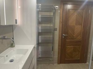a bathroom with a sink and a shower with a wooden door at Luxury Small 1 bed property West London in Perivale