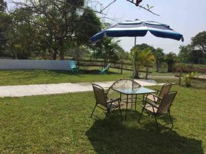 una mesa y sillas bajo una sombrilla en un patio en Casa de vacaciones rancho la chingada, en Tecolutla
