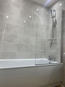 a bathroom with a bath tub with a shower at Brand New Posh 1 Bed Lakeside Flat No parties No Events in West Thurrock