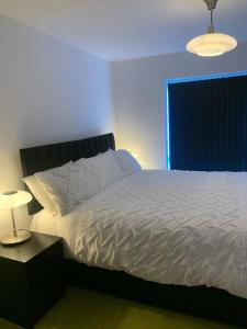 - une chambre avec un lit blanc, une table de chevet et une lampe dans l'établissement Brand New Posh 1 Bed Lakeside Flat No parties No Events, à West Thurrock