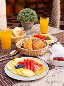 een tafel met borden fruit en brood en glazen sinaasappelsap bij Viva Merida Hotel Boutique in Mérida