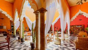 梅里达Viva Merida Hotel Boutique的一间设有白色窗帘和桌椅的餐厅