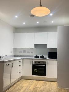 an empty kitchen with white cabinets and aendant light at Brand New Posh 1 Bed Lakeside Flat No parties No Events in West Thurrock