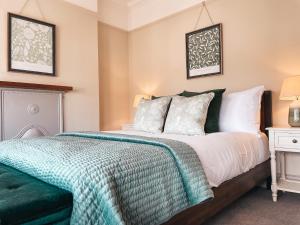 a bedroom with a bed with a green blanket on it at Ty Fry Gardens in Cardiff