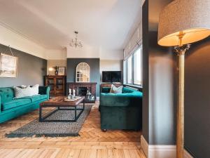 una sala de estar con sofás azules y una lámpara de pie. en Ty Fry Gardens, en Cardiff