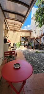 a red table with a bowl on it on a patio at Altea Hostal in Santa Ana
