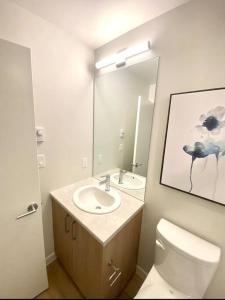 a bathroom with a sink and a toilet and a mirror at Perfect Brand New Condo Downtown Sidney in Sidney