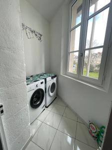eine Waschmaschine in einem weißen Zimmer mit Fenster in der Unterkunft Studio à Centre ville de BRIVE LA GAILLARDE in Brive-la-Gaillarde