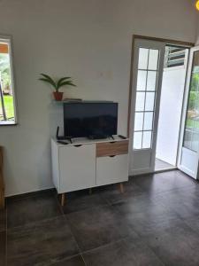 a living room with a tv on a white wall at Maison de campagne avec piscine et spa in Lamentin