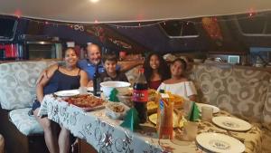a group of people sitting around a table with food at Catamaran El Pelegrino in Les Anses-dʼArlets