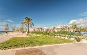 ピネダ・デ・マールにあるNice Apartment In Pineda De Marのヤシの木や建物が並ぶビーチの隣の公園 +18枚の写真