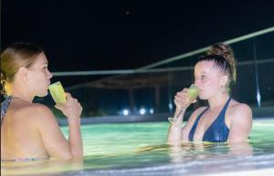 two women in a swimming pool drinking juice at HOTEL ALKQUIMIA in Bayahibe
