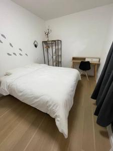 Schlafzimmer mit einem großen weißen Bett und einem Schreibtisch in der Unterkunft Appartement T2 à centre ville in Brive-la-Gaillarde
