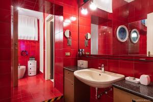 La salle de bains rouge est pourvue d'un lavabo et d'un miroir. dans l'établissement Billie's Flat RED - art & design apt in Verona historic centre, à Vérone