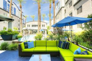 a green couch with a blue umbrella and palm trees at Loft with Views-King Beds-Shop & Dine-1mi & Parking 4058 in Phoenix
