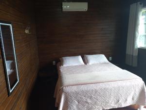 a bedroom with a bed with white sheets and a mirror at Fazenda Morro Das Torres in Urupema