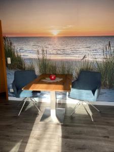 einen Tisch und zwei Stühle vor einem Strand in der Unterkunft Ferienwohnung OstseeStrandLäufer 3 in Zingst