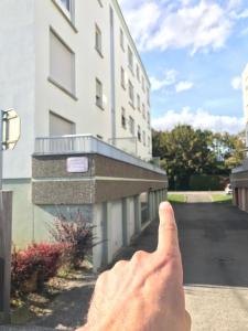 une main pointant vers un bâtiment dans l'établissement Studio T à 5mn euro airport avec terrasse, à Saint-Louis