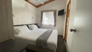 a bedroom with a white bed and a window at Twin Dolphins Holiday Park in Tuncurry