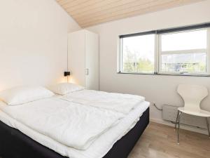 1 dormitorio blanco con 1 cama grande y 1 silla en Holiday home Brovst XIX, en Brovst