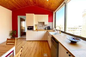 a kitchen with white cabinets and a red wall at Wooden Turkish Style Apt in Umm Uthainah