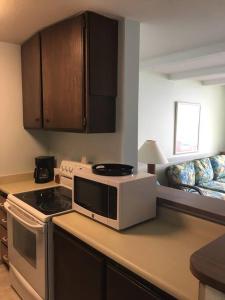 a kitchen with a stove and a microwave on a counter at Beautiful Oceanfront Welcomes you at Hale Kona Kai 203 by Casago Kona in Kailua-Kona