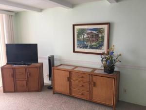 a living room with a tv and a wooden dresser with a tvictericter at Beautiful Oceanfront Welcomes you at Hale Kona Kai 203 by Casago Kona in Kailua-Kona
