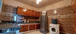 cocina con armarios de madera, lavadora y secadora en Appartement ahfir en Ahfir