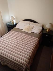 a bedroom with a bed with two nightstands and two lamps at Comodo Departamento in San Juan