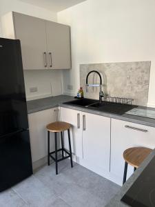 a kitchen with white cabinets and a sink and two stools at Hackney Apartment in London