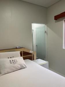 1 dormitorio con cama blanca y ducha acristalada en Hotel Carrão, en São Paulo