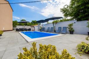 a pool with chairs and umbrellas in a backyard at Family friendly house with a swimming pool Smoljanci, Central Istria - Sredisnja Istra - 20873 in Svetvinčenat
