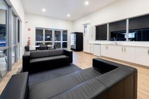 a living room with two black couches and a kitchen at BIG4 Emu Beach Holiday Park in Albany