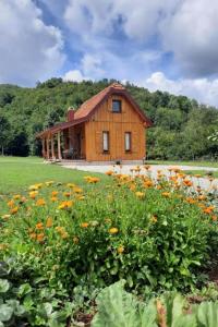 ein Holzhaus mit einem Blumenfeld davor in der Unterkunft Family friendly house with a swimming pool Gospic, Velebit - 21171 in Gospić