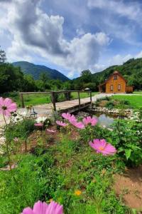 einen Garten mit rosa Blumen und einer Holzbrücke in der Unterkunft Family friendly house with a swimming pool Gospic, Velebit - 21171 in Gospić