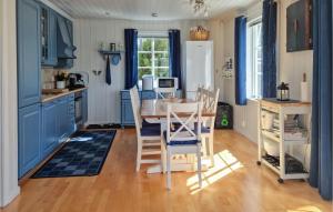uma cozinha com armários azuis e uma mesa e cadeiras em Amazing Home In Risr With Wifi em Risør